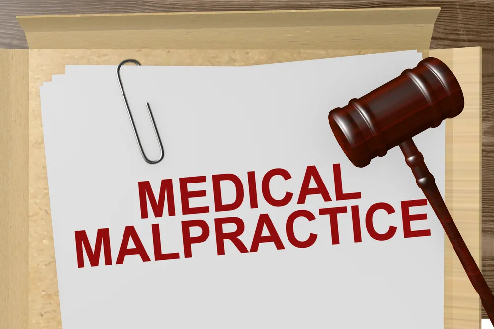 papers being held by a paper clip with the words "medical malpractice" large typed in red. A gavel is on top of the papers.