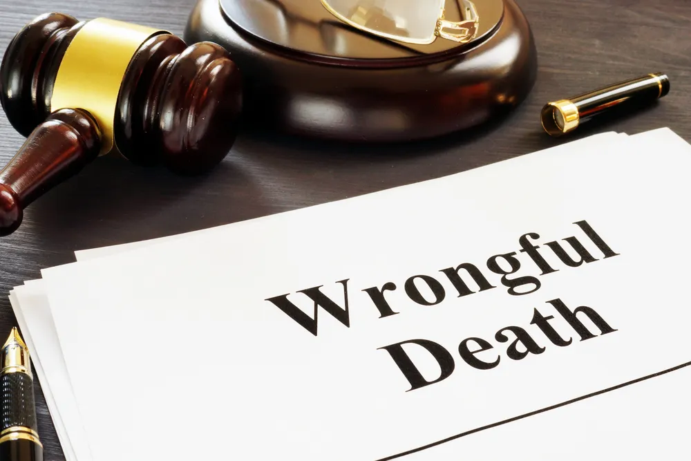 Stack of papers next to a gavel that read "Wrongful Death" in large black typeface.