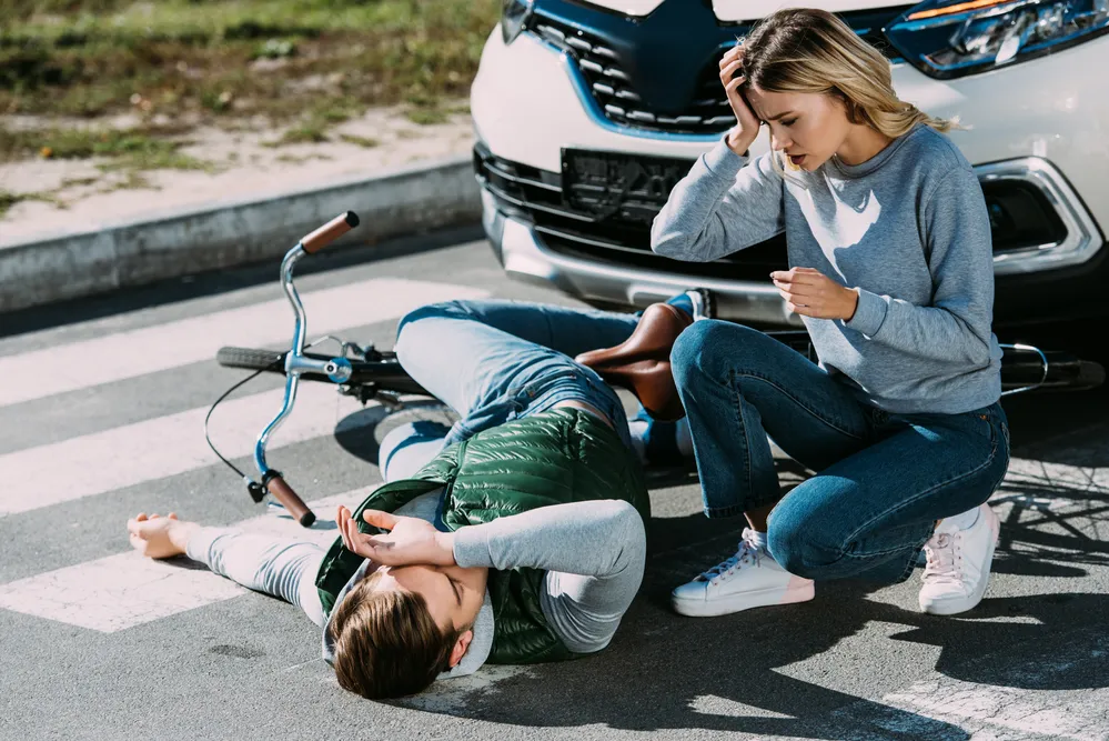 Woman checking on a man on the ground who was hit by her car.