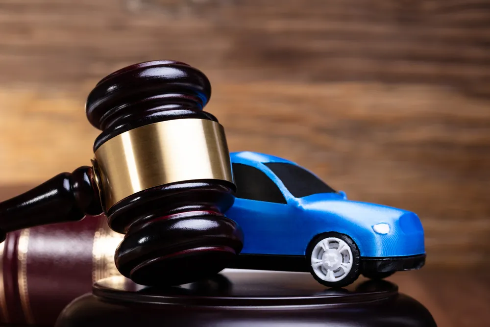Very close up of a gavel with a toy blue car behind it.