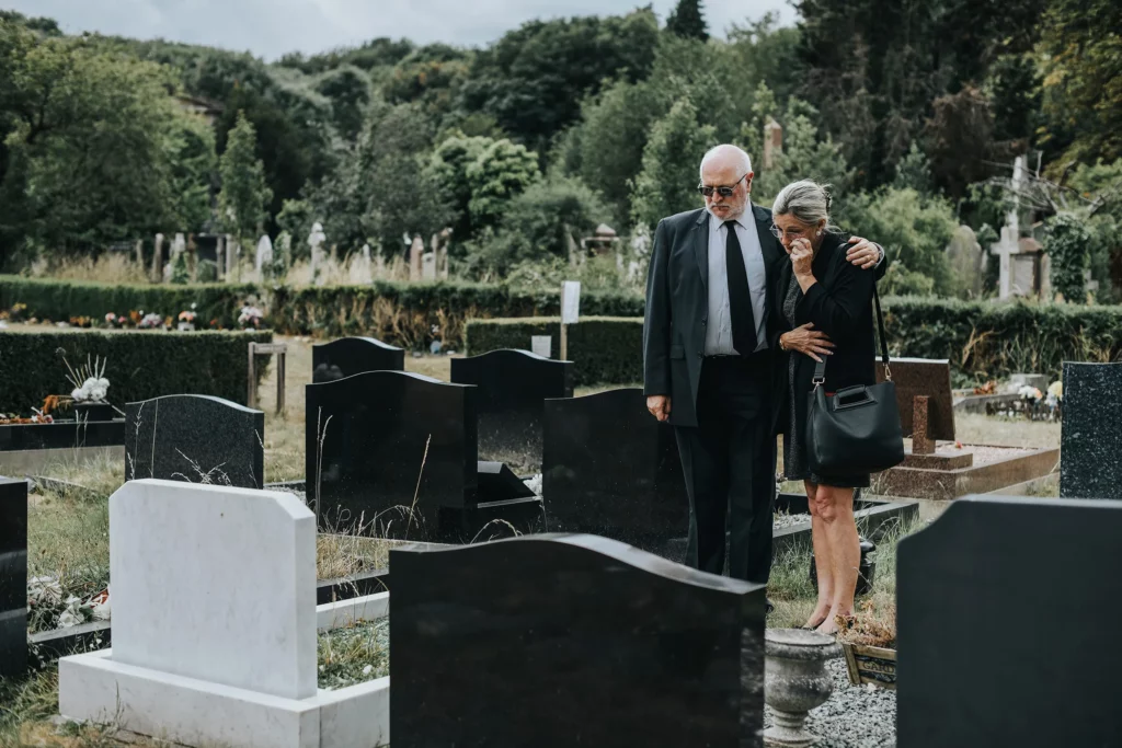 Sad elderly man and woman staring at a tombstone. If you've lost a loved one due to negligence, our Kansas City personal injury lawyers are ready to fight for you. 