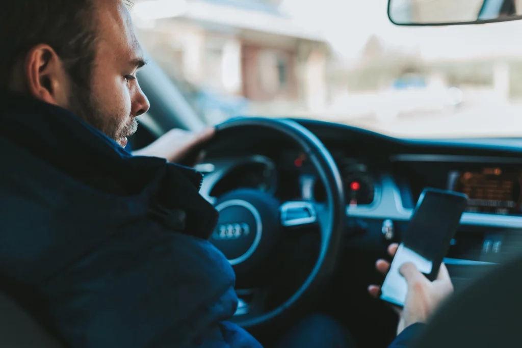 A driver distracted by their phone and about to get into an accident. If you've been in an accident call a distracted driver accident attorney in Kansas City.
