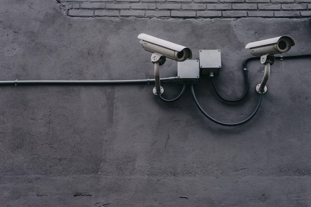 two security cameras on a cement wall.